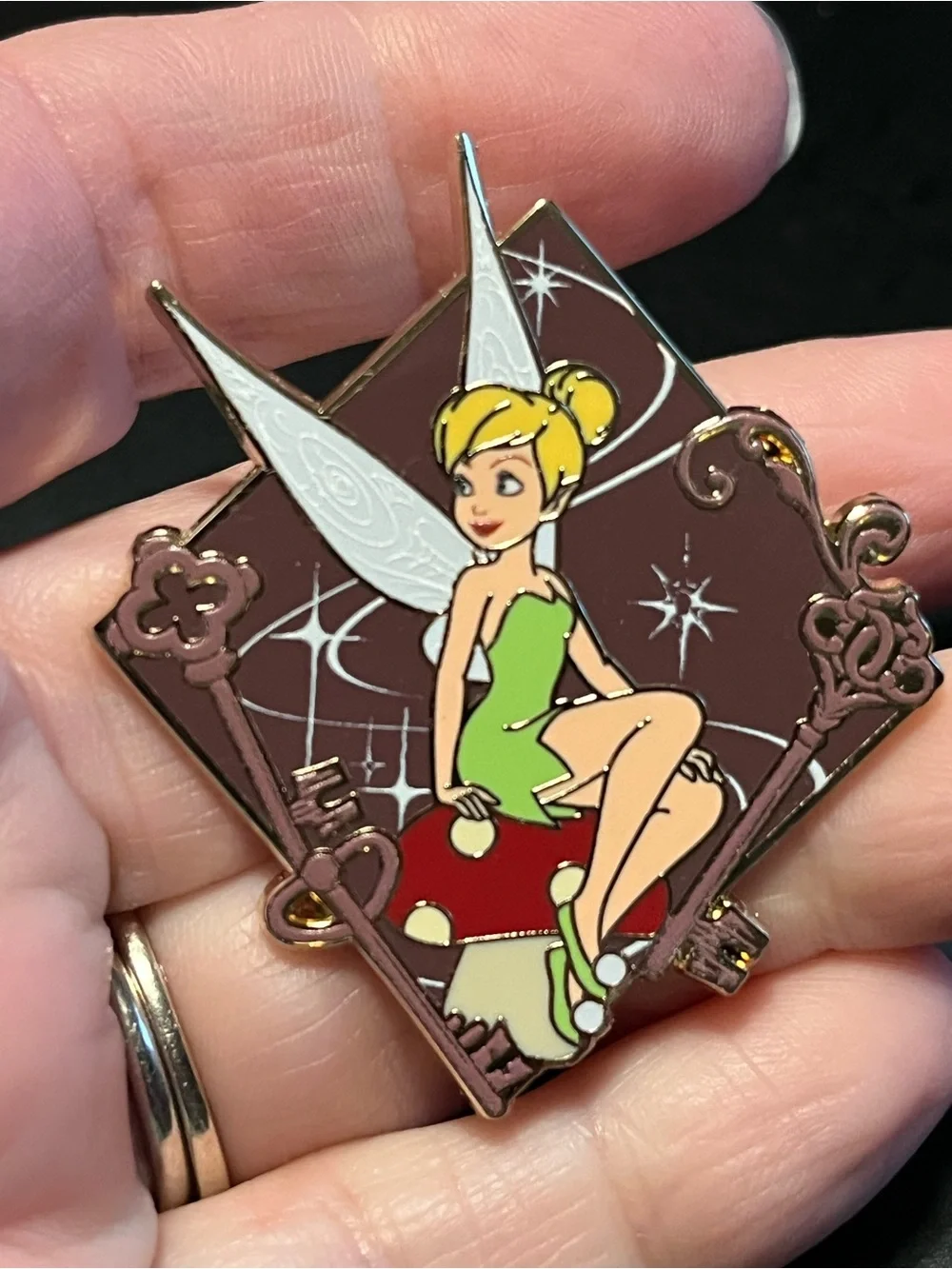 Disney Tinker Bell Pin, mushrooms and keys on brown background
